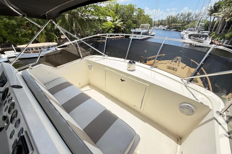 Slide: The Image of 1978 Hatteras 53 Motor Yacht helm with striped seating, overlooking a serene marina. - 36