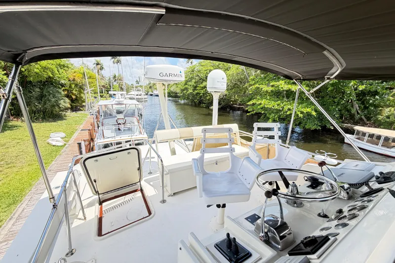 Slide: The Image of 1978 Hatteras 53 Motor Yacht helm with Garmin equipment, docked by lush greenery. - 37