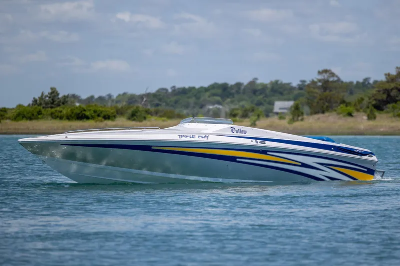 The Image of 2014 Baja 35 Outlaw speedboat cruising on a calm lake with scenic background. - 0