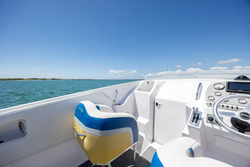 Slide: The Image of 2014 Baja 35 Outlaw boat interior with blue and yellow seating, steering wheel, and ocean view. - 13