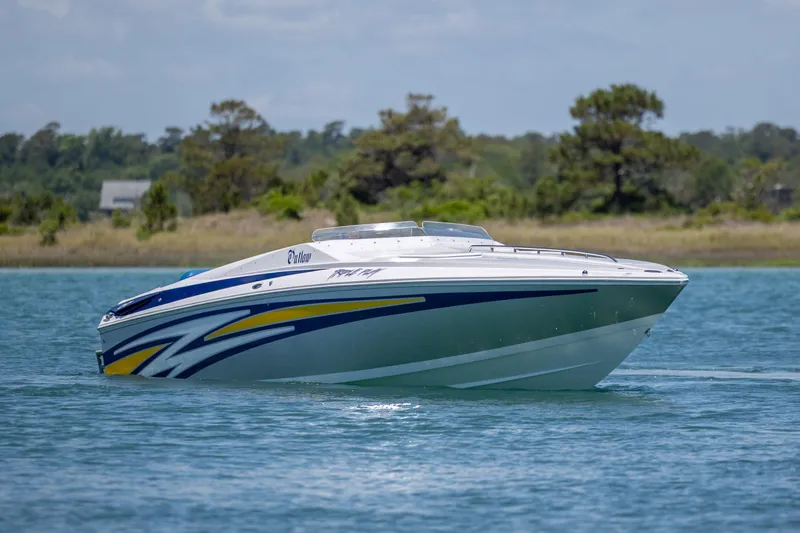 Slide: The Image of 2014 Baja 35 Outlaw speedboat cruising on a serene lake with scenic background. - 3