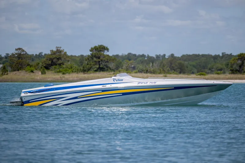 Slide: The Image of 2014 Baja 35 Outlaw speedboat cruising on a serene lake with scenic background. - 5
