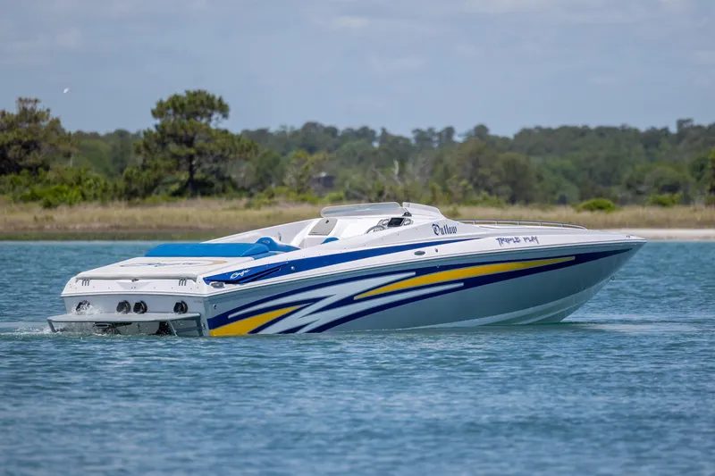 Slide: The Image of 2014 Baja 35 Outlaw speedboat cruising on a serene lake with scenic background. - 6