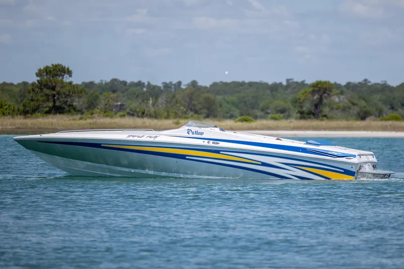 Slide: The Image of 2014 Baja 35 Outlaw speedboat cruising on a serene lake with scenic background. - 9