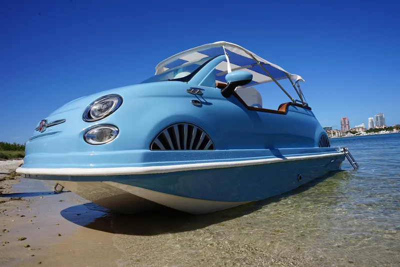Slide: The Image of A blue 2025 Car Off-shore Fiat 500 Classic boat on a sunny beach. - 5