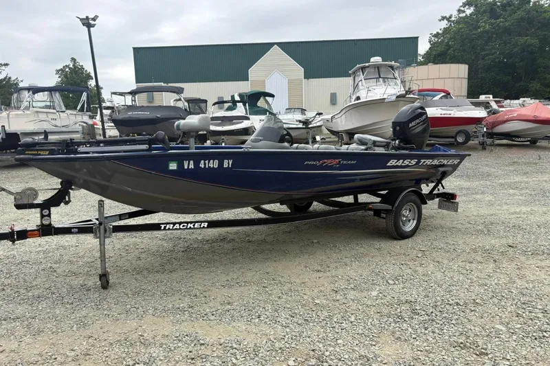Slide: The Image of 2015 Tracker Pro Team 175 TF boat on trailer, parked in a gravel lot with other boats. - 3