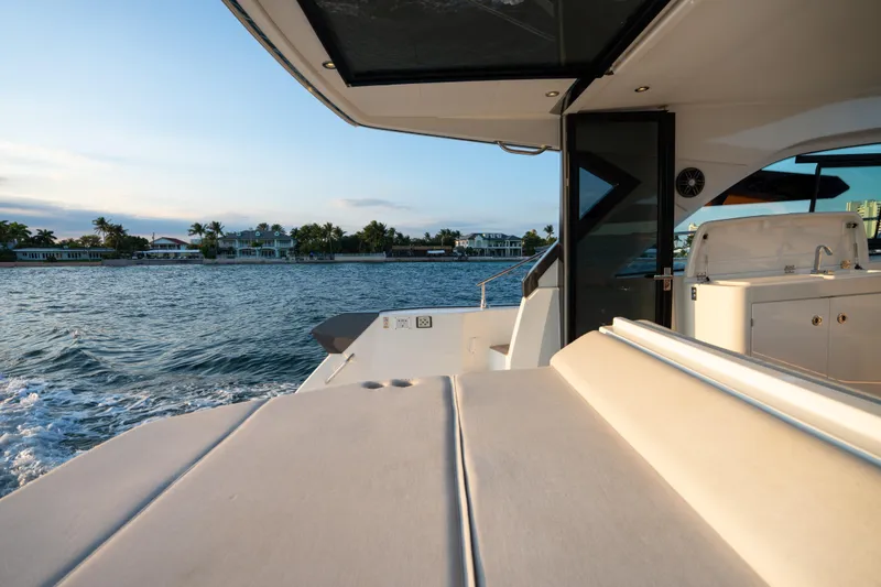 Slide: The Image of 2023 Beneteau Gran Turismo 45 yacht cruising near waterfront homes at sunset. - 49