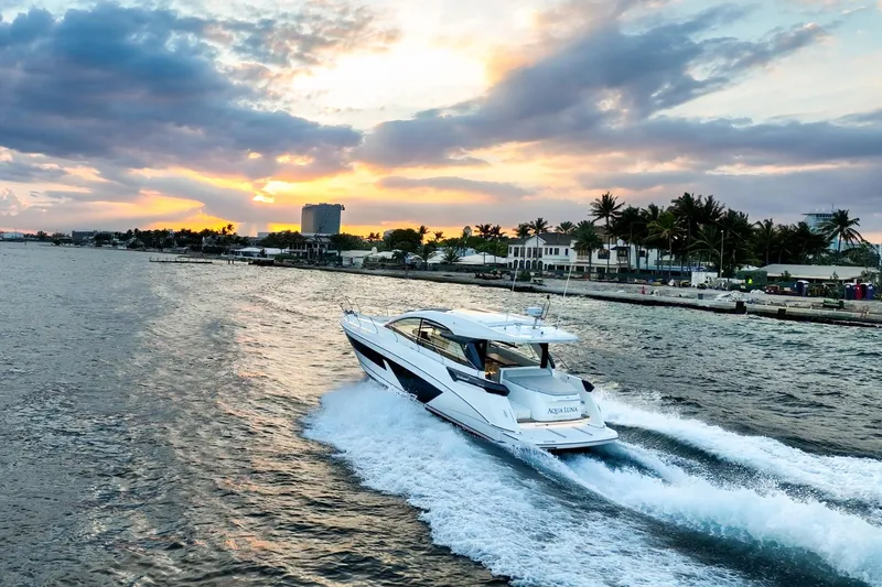 Slide: The Image of 2023 Beneteau Gran Turismo 45 yacht cruising at sunset near a coastal city. - 6