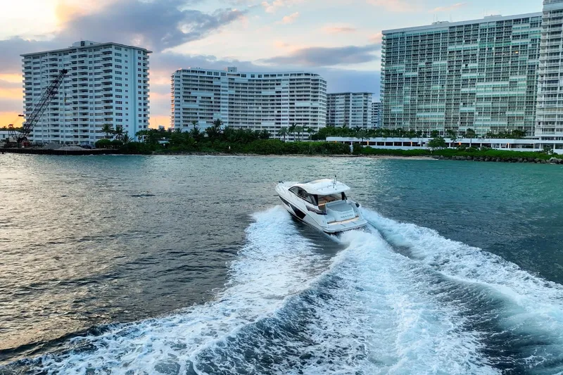 Slide: The Image of 2023 Beneteau Gran Turismo 45 cruising near waterfront buildings at sunset. - 7