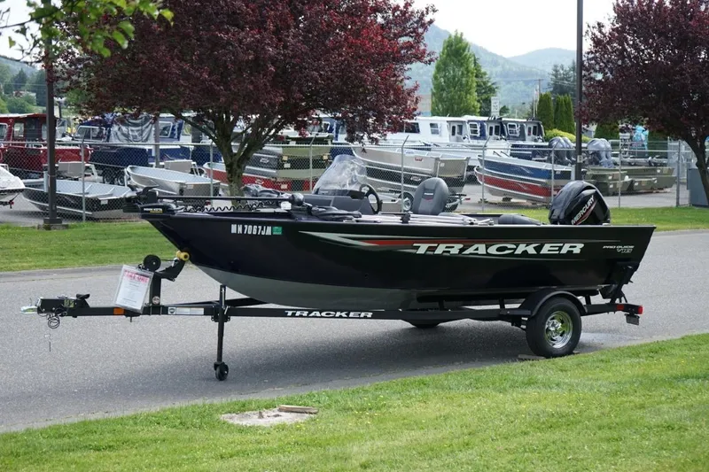 Slide: The Image of 2025 TRACKER BOATS Pro Guide V16 SC on trailer, parked outdoors near other boats. - 14
