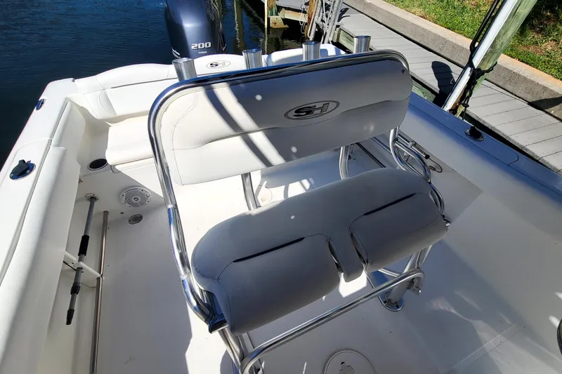 Slide: The Image of 2017 Sea Hunt Ultra 225 boat interior with seating and motor, docked by the water. - 11