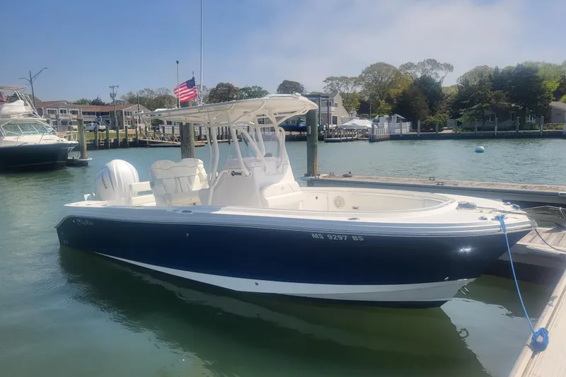 The Image of 2022 Edgewater 245CC boat docked in a marina, featuring a sleek blue and white design. - 0