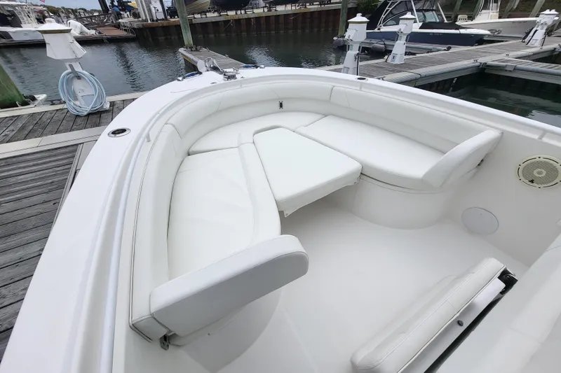 Slide: The Image of 2022 Edgewater 245CC boat with white cushioned seating at a marina dock. - 12