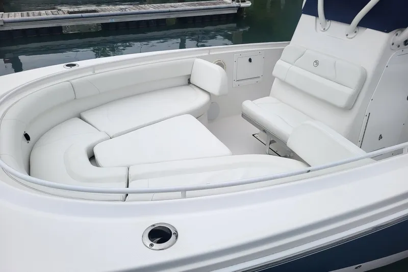 Slide: The Image of 2022 Edgewater 245CC boat with white cushioned seating in a marina setting. - 13