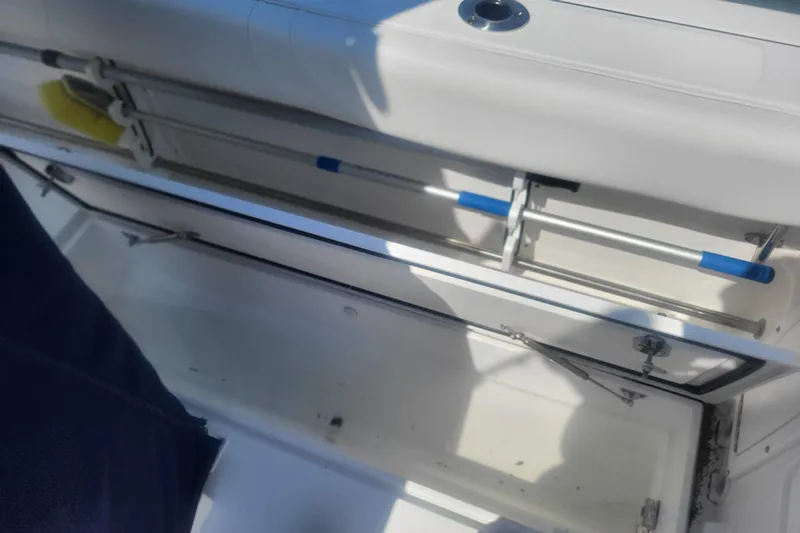 Slide: The Image of Open storage compartment on a 2022 Edgewater 245CC boat, featuring metal rods and a clean interior. - 28