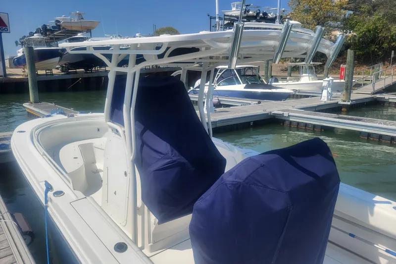 Slide: The Image of 2022 Edgewater 245CC boat docked, featuring covered seats and a T-top, in a marina setting. - 3