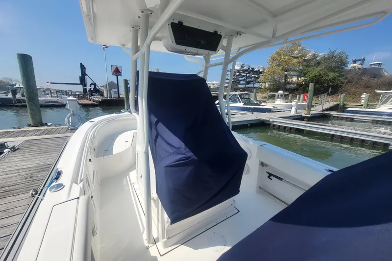 Slide: The Image of 2022 Edgewater 245CC boat docked at marina, featuring covered seating and clear blue sky. - 32