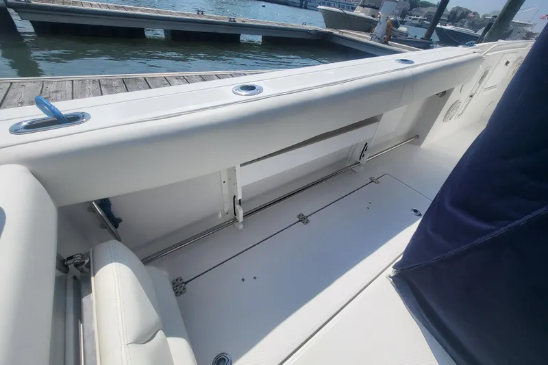 Slide: The Image of 2022 Edgewater 245CC boat interior with white seating and storage, docked by the water. - 35