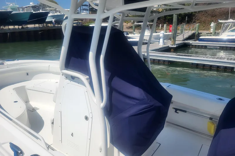 Slide: The Image of 2022 Edgewater 245CC boat interior with covered seating at a marina. - 4