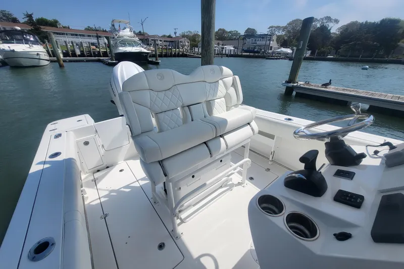 Slide: The Image of 2022 Edgewater 245CC boat interior with white seating and steering console at a marina. - 40
