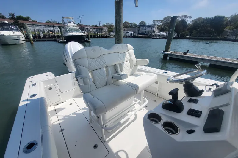 Slide: The Image of 2022 Edgewater 245CC boat interior with plush seating and modern controls at a marina. - 42