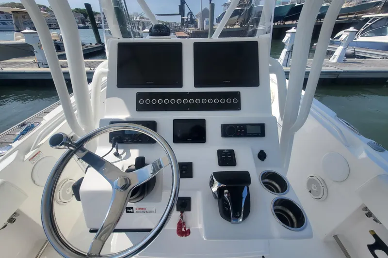 Slide: The Image of 2022 Edgewater 245CC boat dashboard with steering wheel, controls, and navigation screens. - 58
