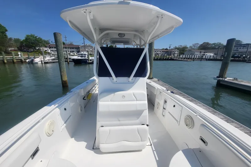 Slide: The Image of 2022 Edgewater 245CC boat interior at dock, featuring spacious seating and helm. - 7