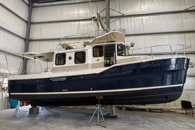 The Image of 2025 Ranger Tugs R-31 CB boat in a warehouse, elevated on stands. - 0