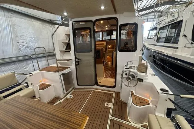 Slide: The Image of 2025 Ranger Tugs R-31 CB boat interior with wood flooring and seating in a marina setting. - 10