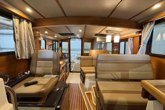 Slide: The Image of Interior of 2025 Ranger Tugs R-31 CB, featuring luxurious seating and wood accents. - 17