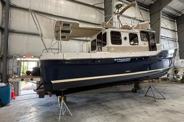 Slide: The Image of 2025 Ranger Tugs R-31 CB boat in a warehouse, elevated on stands. - 2