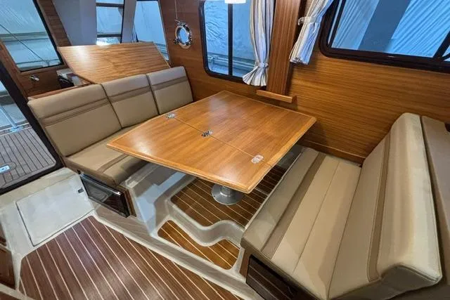 Slide: The Image of 2025 Ranger Tugs R-31 CB interior with wood accents and beige seating in dining area. - 21