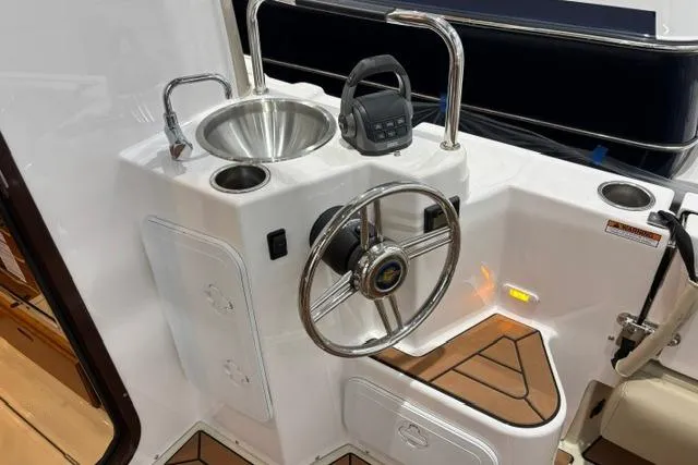 Slide: The Image of 2025 Ranger Tugs R-31 CB helm with steering wheel, sink, and control panel. - 8
