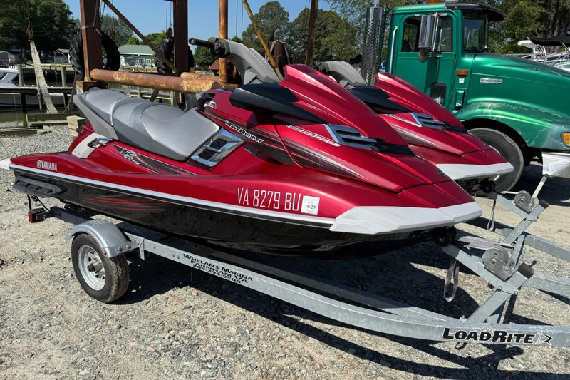 The Image of Red 2013 Yamaha WaveRunner FX HO jet skis on a LoadRite trailer, parked outdoors. - 0