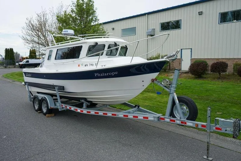 The Image of 2021 Sea Sport Explorer 2400 boat on trailer, parked near industrial building. - 1