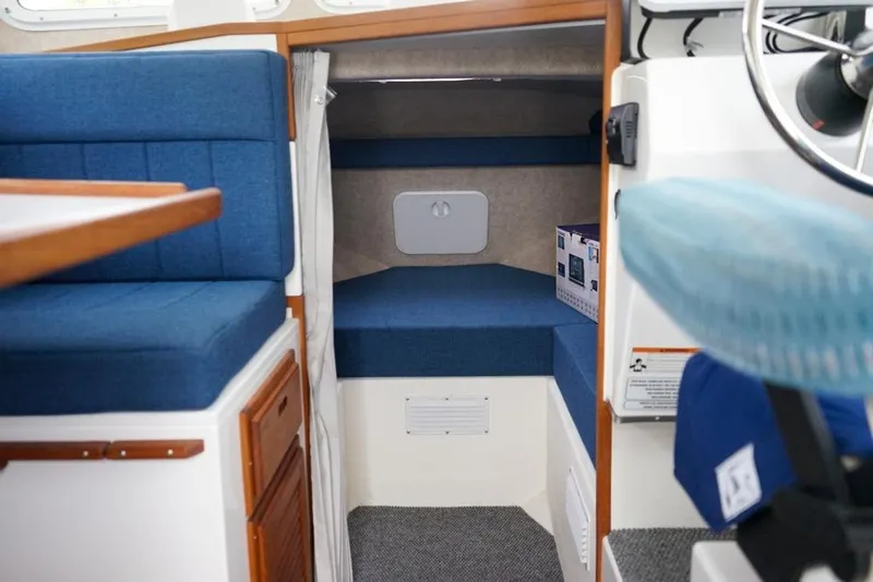Slide: The Image of Interior of 2021 Sea Sport Explorer 2400 boat with blue seating and compact cabin space. - 14