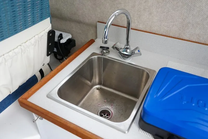 Slide: The Image of 2021 Sea Sport Explorer 2400 interior sink with faucet and blue storage box. - 16
