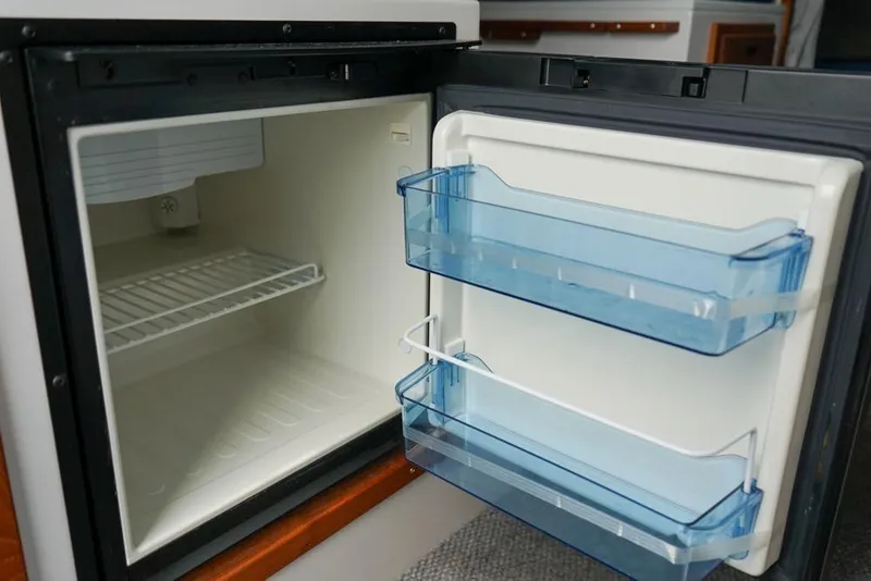 Slide: The Image of Open refrigerator inside a 2021 Sea Sport Explorer 2400 boat, featuring blue door shelves. - 20