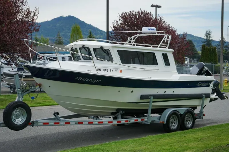 Slide: The Image of 2021 Sea Sport Explorer 2400 boat on trailer, parked outdoors with scenic mountain backdrop. - 21
