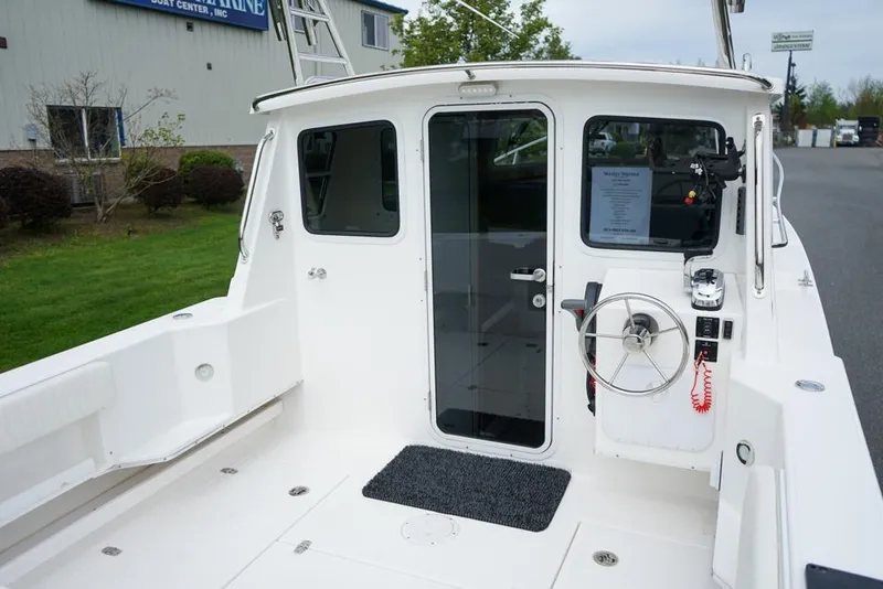 Slide: The Image of 2021 Sea Sport Explorer 2400 boat cockpit with steering wheel and glass door. - 5