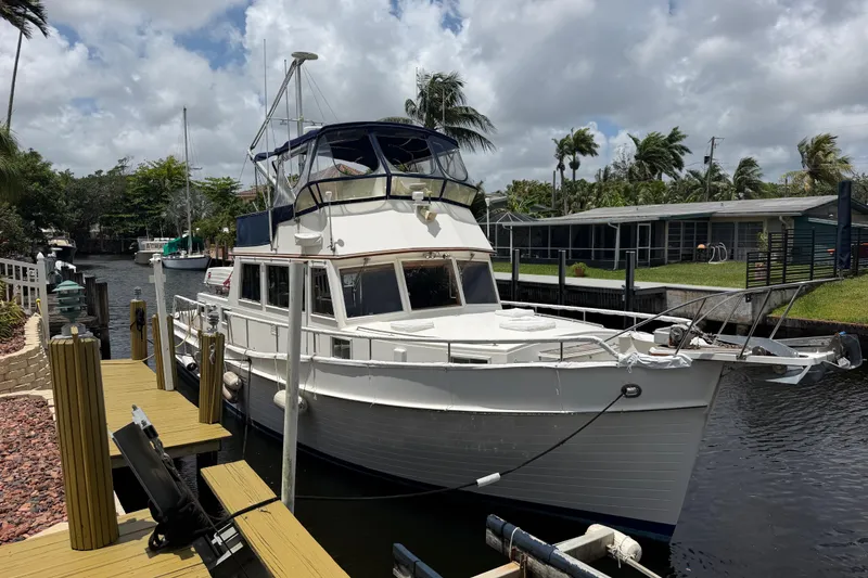 The Image of 1991 Grand Banks 46 Classic yacht docked by a canal under a cloudy sky. - 1