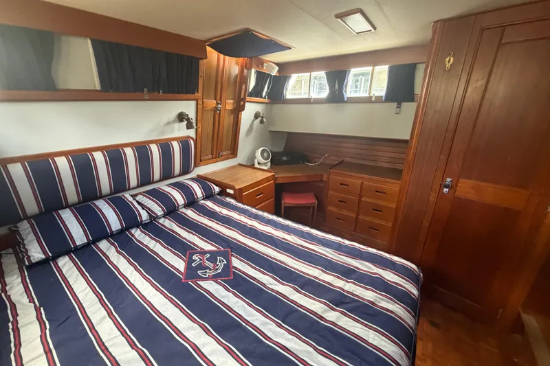 Slide: The Image of 1991 Grand Banks 46 Classic yacht cabin with striped bedding and wooden furnishings. - 21