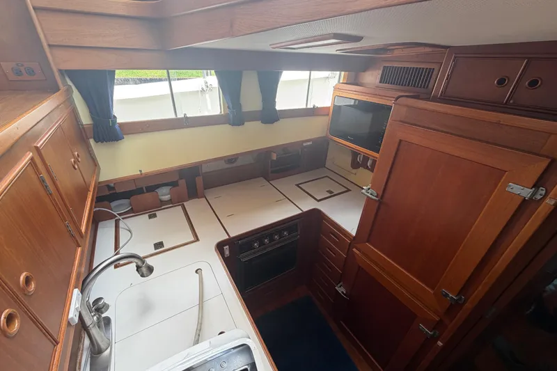 Slide: The Image of Interior of 1991 Grand Banks 46 Classic yacht, featuring a well-equipped wooden kitchen. - 30