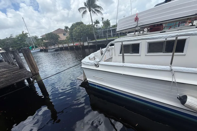 Slide: The Image of 1991 Grand Banks 46 Classic yacht docked by a wooden pier, surrounded by calm water. - 33