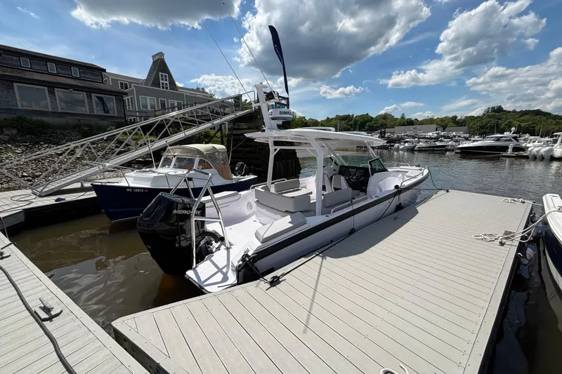 Slide: The Image of 2025 Axopar 29 Sun-Top boat docked at a marina under a partly cloudy sky. - 11