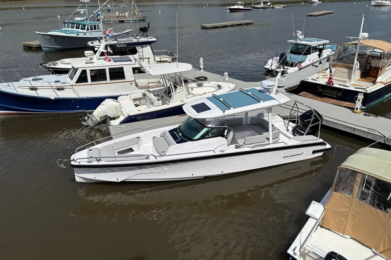 Slide: The Image of 2025 Axopar 29 Sun-Top boat docked among other vessels in a marina. - 13