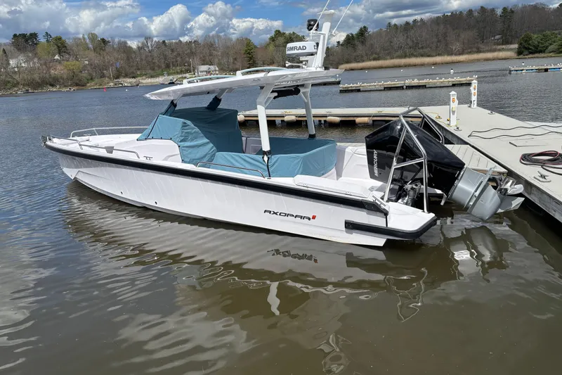 Slide: The Image of 2025 Axopar 29 Sun-Top boat docked on a calm lake under a cloudy sky. - 16