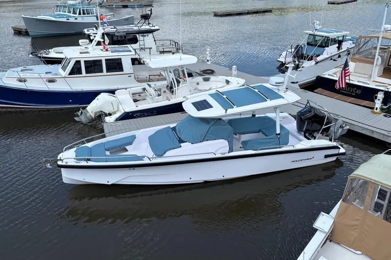 Slide: The Image of 2025 Axopar 29 Sun-Top boat docked in a marina, featuring sleek design and blue seating. - 17