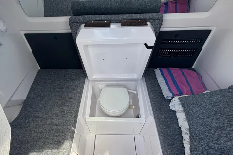 Slide: The Image of 2025 Axopar 29 Sun-Top interior with compact marine toilet and seating area. - 31