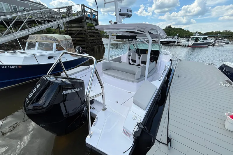 Slide: The Image of 2025 Axopar 29 Sun-Top boat docked, featuring a Mercury engine, under a partly cloudy sky. - 5